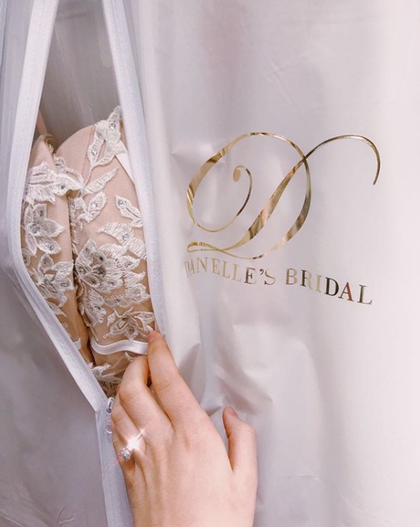 A bride takes a look at her brand new wedding dress from Danelle's Bridal Boutique in Colorado Springs. Each bride gets their dress in a white keepsake garment bag with a gold foil Danelle's logo on it.